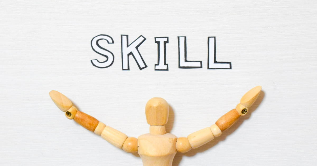 両手を広げた木製人形と「SKILL」の文字
